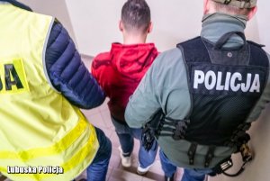 dwaj policjanci prowadzą zatrzymanego