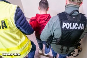 dwaj policjanci prowadzą zatrzymanego