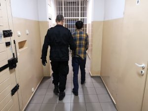 Policjant prowadzi zatrzymanego Gruzina