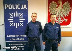 Policjanci stoją za nimi widnieje godło