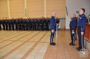 policjant składa meldunek Komendantowi Głównemu Policji w tle policjanci