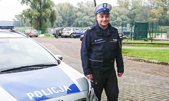 policjant stoi przy radiowozie