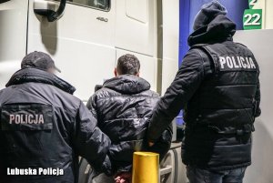 dwaj policjanci prowadzą zatrzymanego mężczyznę