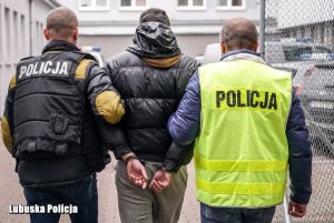 dwaj policjanci prowadzą zatrzymanego mężczyznę