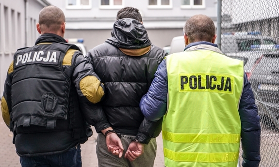 dwaj policjanci prowadzą zatrzymanego mężczyznę