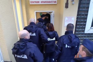 Policjanci wchodzą do stacji krwiodawstwa w Słupsku.