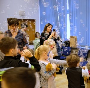 dzieci i dorośli w trakcie zabawy puszczają bańki mydlane