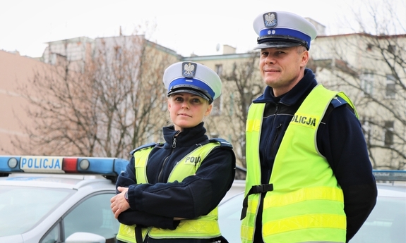 policjant i policjantka przy radiowozie