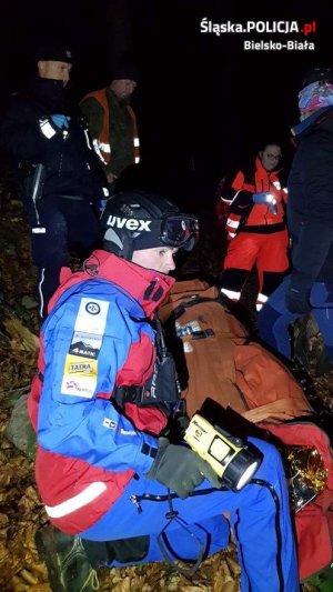 Policjanci i ratownicy GOPR udzielają transportują poszkodowanego na noszach