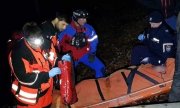 Policjanci i ratownicy GOPR udzielają pomocy poszkodowanemu, umieszczonemu na noszach