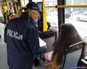 Policjantka przekazuje pasażerce ulotkę informacyjną w tramwaju