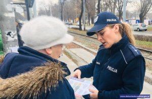 Policjantka przekazuje ulotkę informacyjną mieszkance Wrocławia na przestanku tramwajowym