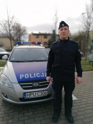 policjant stoi przed radiowozem