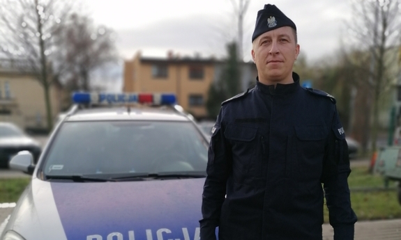 policjant stoi przed radiowozem