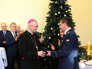 komendant wręcza medal z okazji 100lecia powołania policji arcybiskupowi