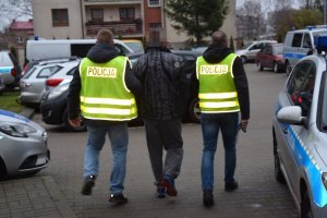 dwaj policjanci prowadzą zatrzymanego mężczyznę