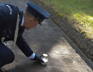 policjant stawia znicz na grobie