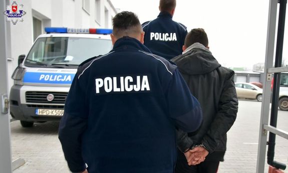 policjanci prowadzą zatrzymanego mężczyznę