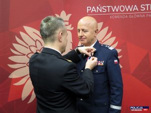 komendant główny Policji gen. insp.  Jarosław Szymczyk z rąk komendanta głównego PSP bryg. mgr. Andrzeja Bartkowiaka otrzymuje Złotą Odznakę „Zasłużony dla Ochrony Przeciwpożarowej” nadawaną przez Ministra Spraw Wewnętrznych i Administracji.