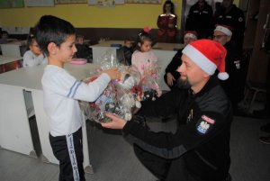policjant wręcza chłopczykowi paczkę świąteczną