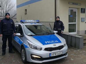 dwaj policjanci stoją przy radiowozie