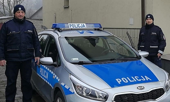 dwaj policjanci stoją przy radiowozie