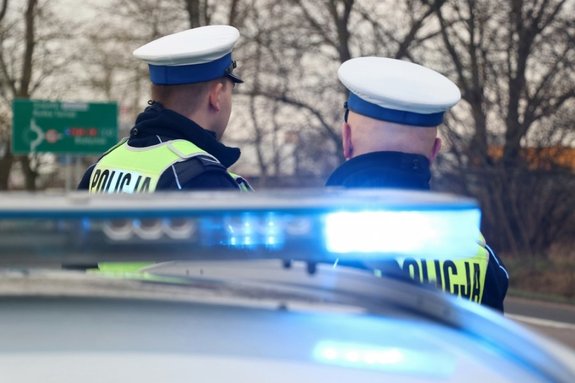 dwaj policjanci stoją obok radiowozu