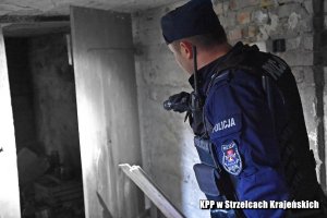 policjant w trakcie sprawdzania pustostanu z latarką w ręku