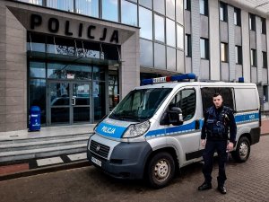 policjant stojący przy radiowozie,który brał udział w wyprowadzaniu mieszkańców płonącej kamienicy