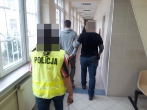 dwaj policjanci prowadzą zatrzymanego mężczyznę