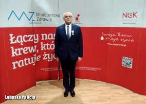 policjant z Gubina stoi z przypiętym medalem na tle biało-czerwonego baneru