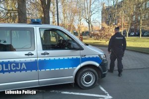 policjant stoi przy radiowozie policjynym