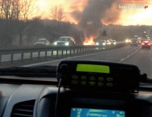 Widok z wnętrza radiowozu na palący się samochód