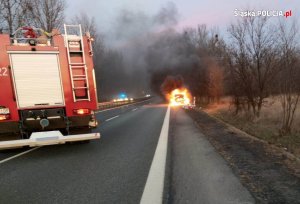 Pojazd straży pożarnej na tle palącego się samochodu