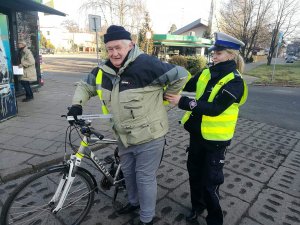 policjantka ruchu drogowego rozdaje odblaski seniorom z okazji dnia babci i dziadka