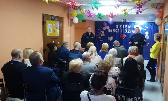 Seniorzy słuchają wykładu policjantów na temat oszustw