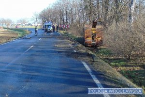 jezdnia na której widać wypadek drogowy, pojazdy ciężarowy w rowie oraz radiowóz policyjny i policjantów zabezpieczających miejsce zdarzenia