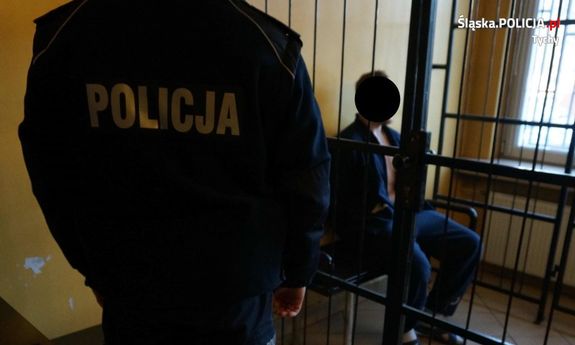 Umundurowany policjant stoi przy zatrzymanym
