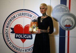 kobieta, w tle logo Fundacji Pomocy Wdowom i Sierotom po poległych policjantach
