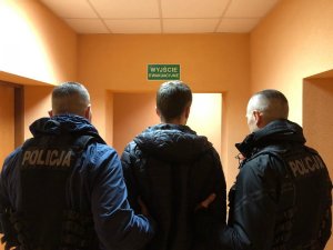 dwaj policjanci prowadzą zatrzymanego męzczyznę