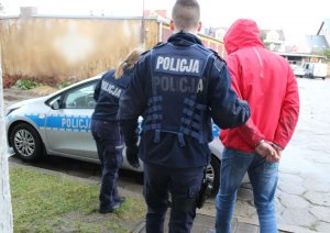 policjanci z zatrzymanym mężczyzną przy radiowozie