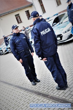 policjant składa meldunek komendantowi podczas uroczystego przekazania radiowozów