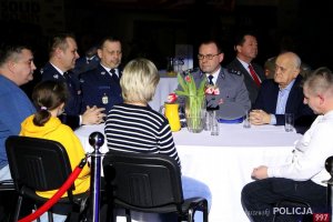 rodzina, goście oraz przedstawiciele służb mundurowych siedzą przy stole podczas XI Międzynarodowego Turnieju Służb Mundurowych w Piłce Nożnej Halowej im. podkom. Andrzeja Struja