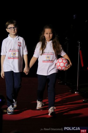 chłopiec i dziewczynka niosą piłkę nożną podczas gali otwarcia XI Międzynarodowego Turnieju Służb Mundurowych w Piłce Nożnej Halowej im. podkom. Andrzeja Struja