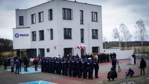 uczestnicy uroczystości stoją przed nowym budynkiem komisariatu Policji