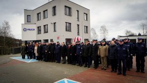 uczestnicy uroczystości stoją przed nowym budynkiem komisariatu Policji