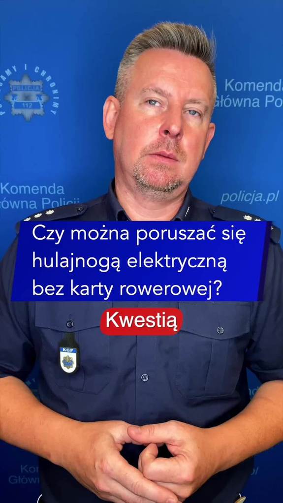 Policjant w letnim umundurowaniu na tle ścianki promocyjnej KGP.