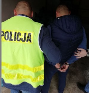 policjant prowadzi zatrzymanego mężczyznę