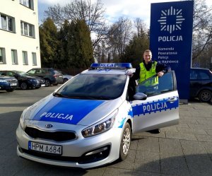 policjant stoi przy radiowozie policyjnym