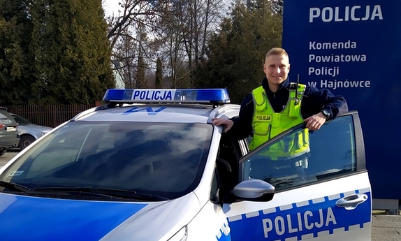 policjant stoi przy radiowozie